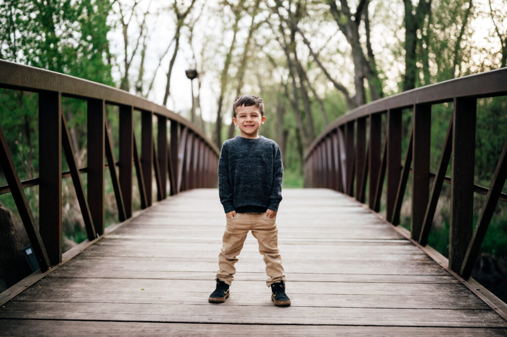 Child standing on a bridge surrounded by tress
