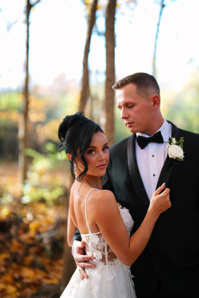 couple poses in fall forest in their wedding attire