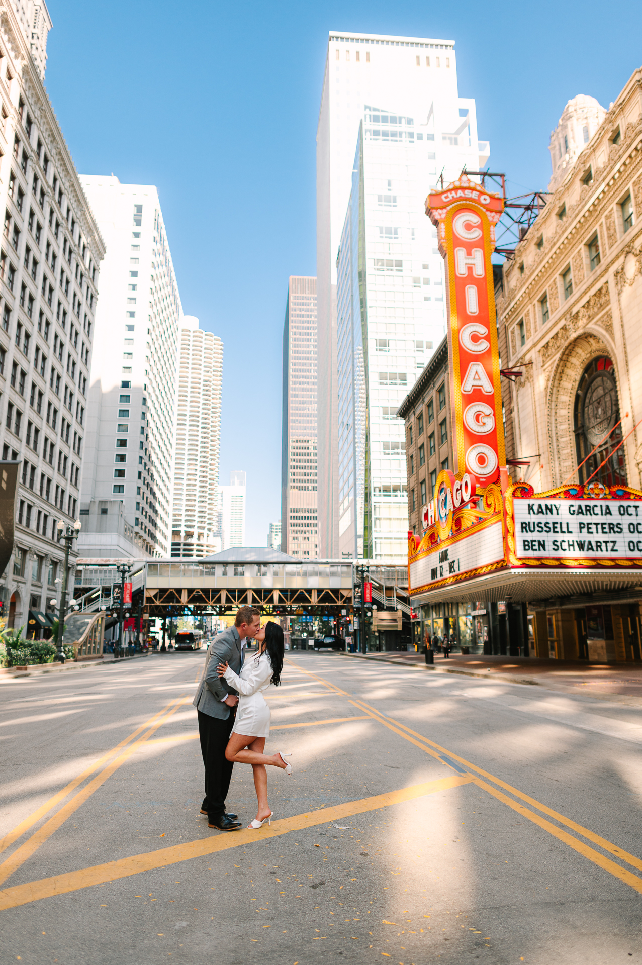 Bride and groom kiss in the middle of the empty street in front of the Chicago Theatre marquee on a Sunday morning during their Chicago elopement